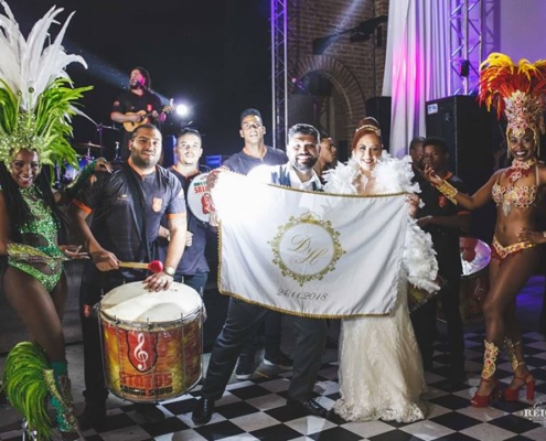 Casal Daiane e Heberson com equipe de bateria Casal Daiane e Heberson com equipe de bateria posando para foto junto com bandeira personalizada